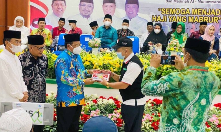 Sekda Prov. Kalteng H. Nuryakin saat menyerahkan secara simbolis sarung dan mukena serta tambahan uang saku untuk Jemaah Calon Haji kepada Ketua Kloter 5 H. Tuani Ismail. (Photo/ist)