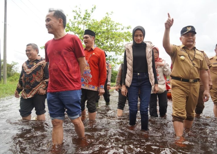 Gubernur Kalteng H. Sugianto Sabran, didampingi Ketua TP-PKK Prov.Kalteng Ivo Sugianto Sabran, Anggota DPR-RI Agustiar Sabran, Pj.Bupati Kobar Anang Dirjo dan Kepala Perangkat Daerah Prov. Kalteng saat menyusuri ruas jalan ke arah menuju Kotawaringin Lama dengan berjalan kaki di tengah genangan banjir. (Photo/ist)